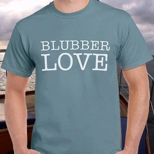 Man wearing a blue T-shirt with the phrase “Blubber Love” printed in bold white letters. Portfolio work by associate creative director and writer Paul Baker for Hornblower Cruises’ proposed “Blubber Club” loyalty program, designed to engage dedicated whale watchers and citizen scientists with exclusive perks and branded merchandise.